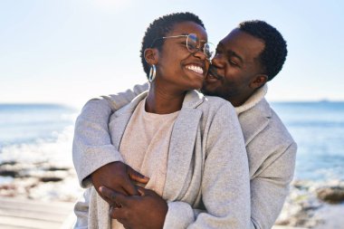 Erkek ve kadın çift sahilde birbirlerine sarılıyorlar.