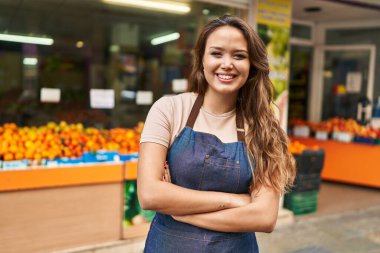 Genç, güzel İspanyol bayan garson, gülümsüyor. Kollarını kavuşturup meyve dükkanına gidiyor.
