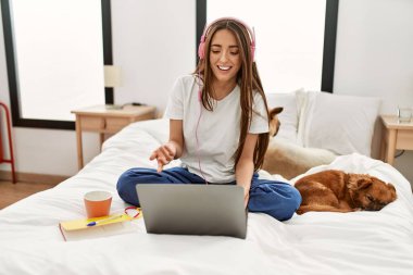 Latin asıllı genç bir kadın yatak odasında köpeklerle otururken görüntülü konuşma yapıyor.