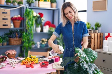 Çiçekçide çalışırken gülümseyen genç kadın.
