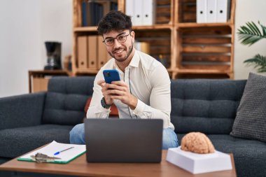 Laptop ve akıllı telefon psikoloji merkezi kullanan genç bir İspanyol psikolog.