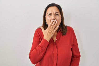 Hispanic mature woman standing over white background bored yawning tired covering mouth with hand. restless and sleepiness. 