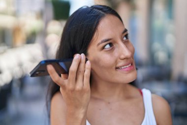 Genç ve güzel İspanyol kadın gülümsüyor. Caddedeki akıllı telefondan kendine güvenen bir sesli mesaj dinliyor.