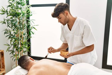 İki İspanyol erkek fizyoterapist ve hasta güzellik merkezinde cilt bakımı yaptırıyor.