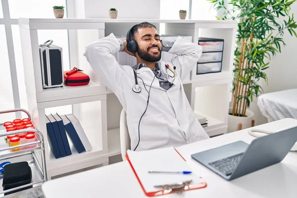Young hispanic man doctor relaxed listening to music at clinic