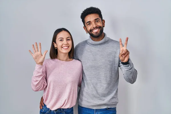 Young Hispanic Couple Standing Together Showing Pointing Fingers Number Seven — 图库照片