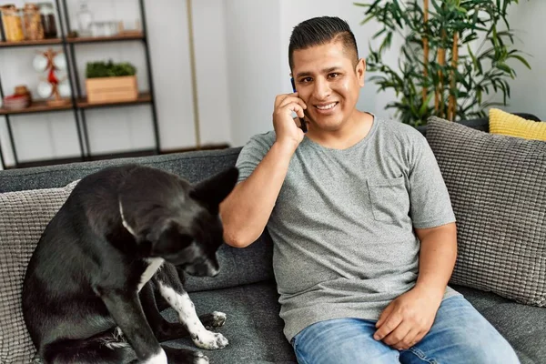 Ung Latinamerikansk Man Pratar Smartphone Sitter Soffan Med Hund Hemma — Stockfoto