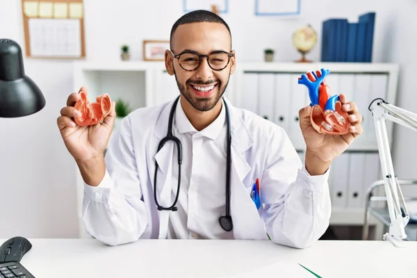 African American Doctor Man Holding Anatomical Heart Clinic Winking Looking — Stockfoto
