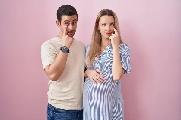 Junges Paar Erwartet Ein Baby Auf Rosa Hintergrund Zeigt Auf — Stockfoto