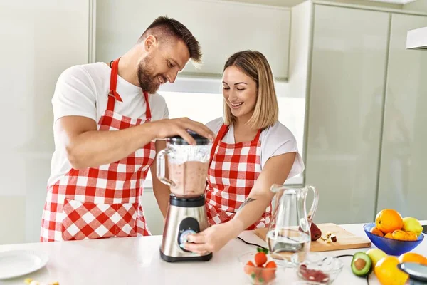 Casal Jovem Sorrindo Confiante Fazendo Smoothie Usando Liquidificador Cozinha — Fotografia de Stock