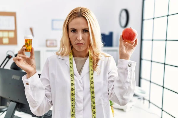Beautiful Blonde Nutritionist Woman Holding Fat Pills Skeptic Nervous Frowning — Stockfoto