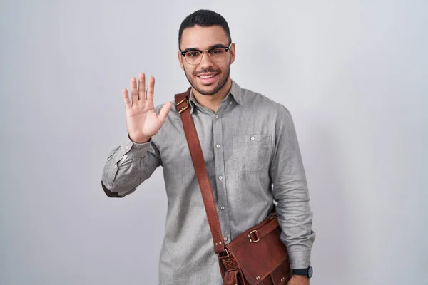 stock image Young hispanic man wearing suitcase waiving saying hello happy and smiling, friendly welcome gesture 