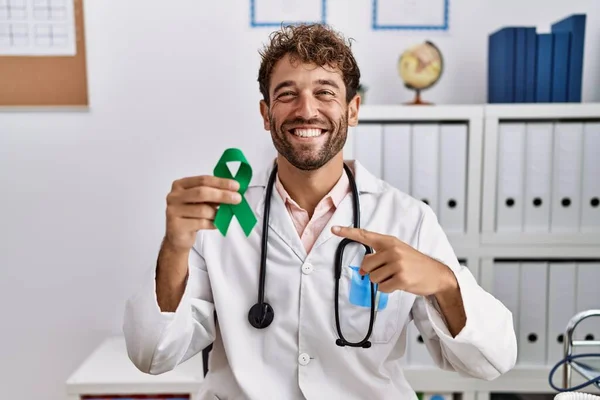 Joven Médico Hispano Sosteniendo Cinta Verde Apoyo Clínica Sonriendo Feliz — Foto de Stock