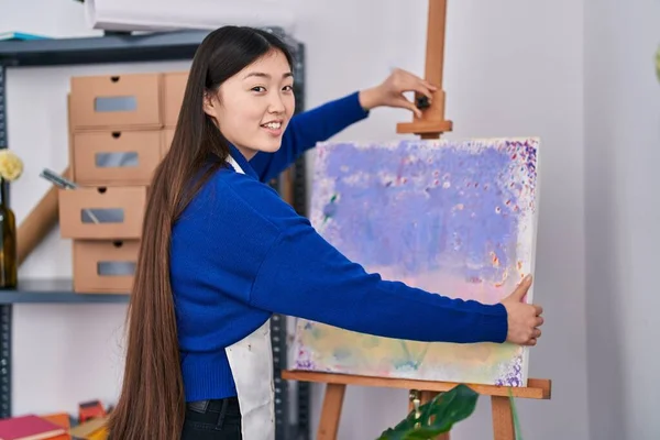 Chinese woman artist smiling confident holding draw at art studio