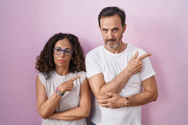 Középkorú Spanyol Házaspár Együtt Rózsaszín Háttér Mutató Kéz Ujját Oldalon — Stock Fotó