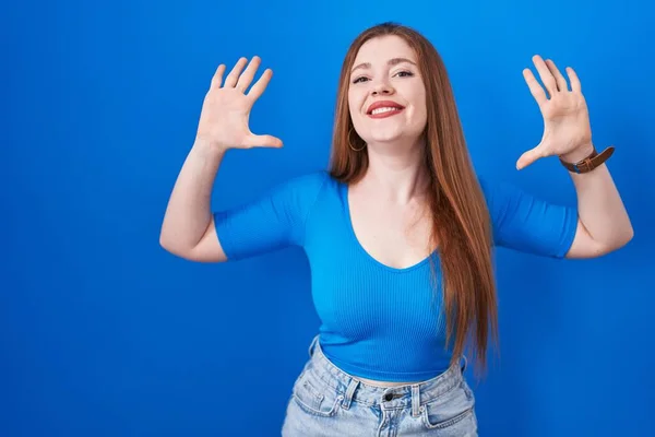 Mavi Arka Planda Duran Kızıl Saçlı Kadın Numarayı Gösterip Işaret — Stok fotoğraf