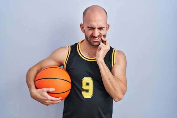 年轻的秃头男子 留着胡子 身穿篮球服 手牵着球 手摸着嘴 因为牙齿疼痛或牙病而有痛苦的表情 牙医概念 — 图库照片