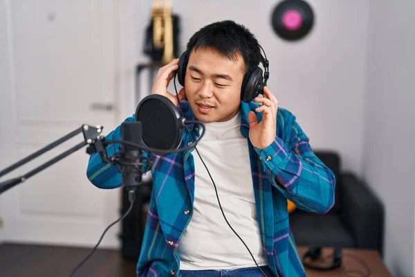 Young chinese man singer singing song at music studio