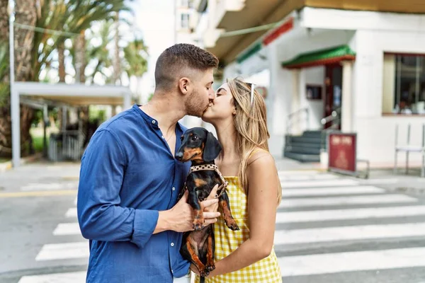 若いですCaucasianカップル抱擁とキス立って犬とともに街 — ストック写真