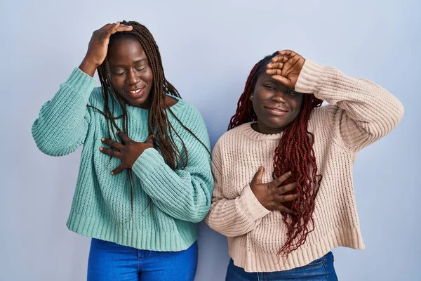 病気と熱 インフルエンザと風邪 ウイルス病のための額に触れる青い背景に立っている2人のアフリカの女性 — ストック写真