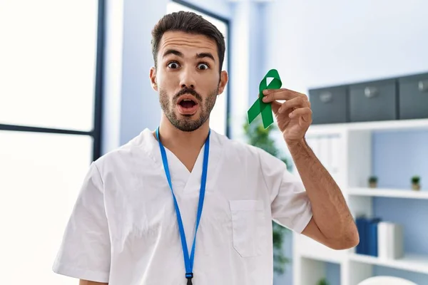 Young Hispanic Doctor Man Holding Support Green Ribbon Clinic Scared — Stockfoto