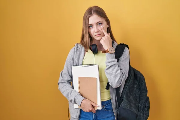 Young Caucasian Woman Wearing Student Backpack Holding Books Pointing Eye — ストック写真