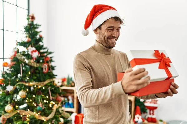 Joven Hombre Hispano Sonriendo Confiado Sosteniendo Regalo Navidad Casa —  Fotos de Stock
