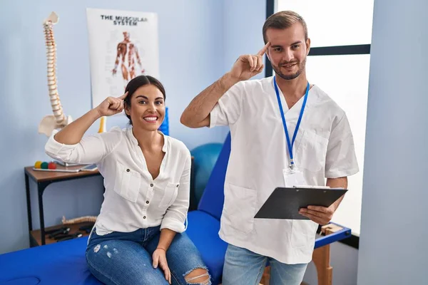 Young Hispanic Woman Physiotherapist Appointment Smiling Pointing Head One Finger — Stockfoto