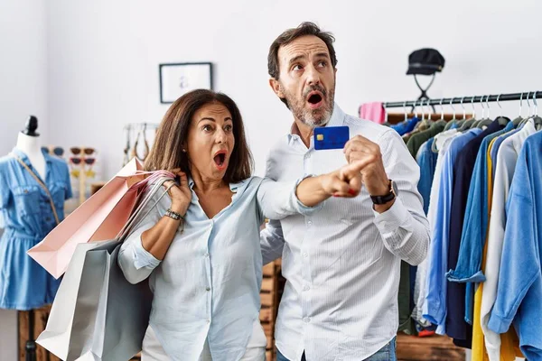 ヒスパニック系の中年のカップルを保持ショッピングバッグやクレジットカード指を指して先に驚いて 口を開けて驚くような表現は フロントに何か — ストック写真