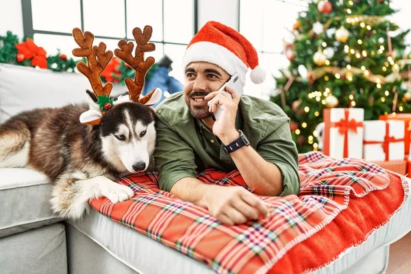 Jovem Hispânico Falando Smartphone Deitado Sofá Com Cão Pela Árvore — Fotografia de Stock
