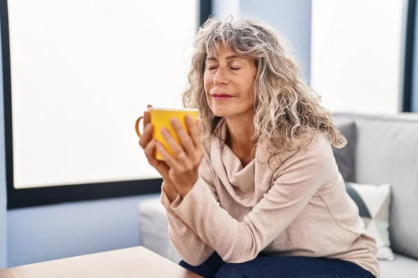 Orta Yaşlı Kadın Evdeki Kanepede Oturup Kahve Içiyor — Stok fotoğraf