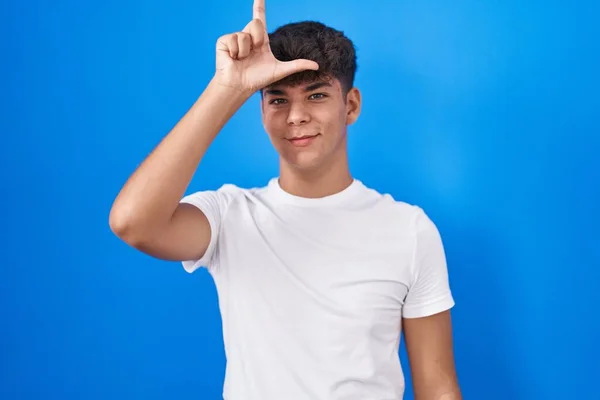 Hispánský Teenager Stojící Nad Modrým Pozadím Dělat Legraci Lidí Prsty — Stock fotografie
