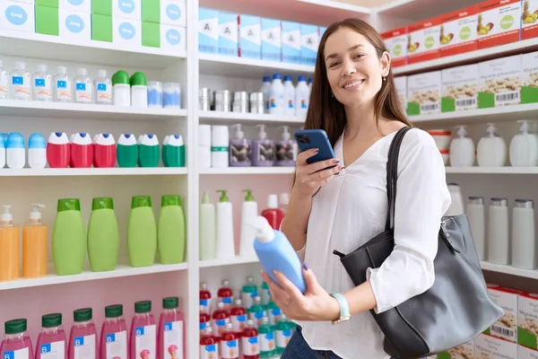年轻漂亮的女顾客在药店用智能手机给洗发水瓶拍照 — 图库照片
