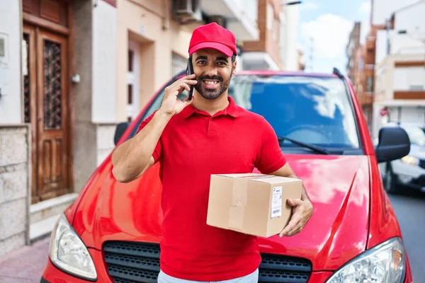 Young Hispanic Man Courier Talking Smartphone Holding Package Street — Stok fotoğraf