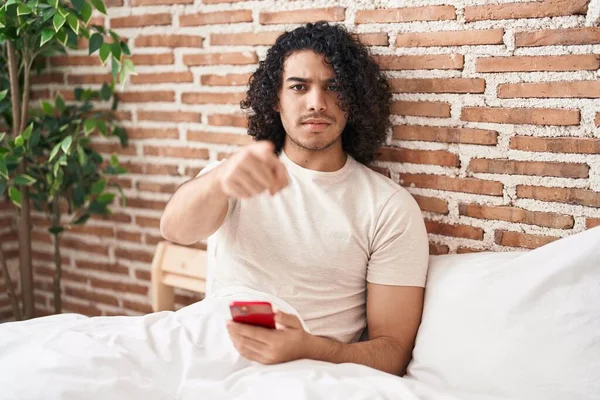 Kıvırcık Saçlı Akıllı Telefonlu Spanyol Bir Adam Yatakta Oturmuş Kamerayı — Stok fotoğraf