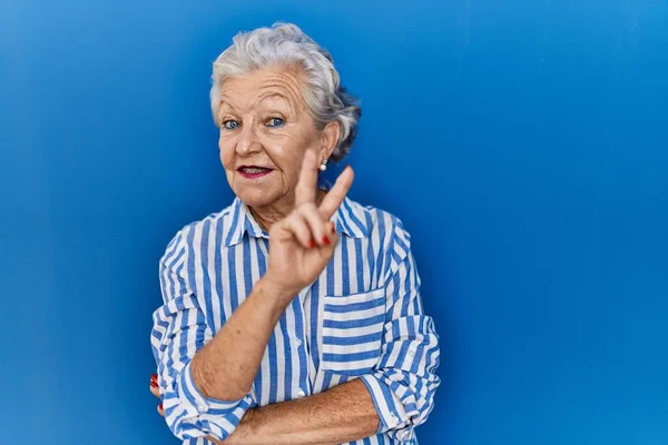 Eine Ältere Frau Mit Grauen Haaren Steht Vor Blauem Hintergrund — Stockfoto