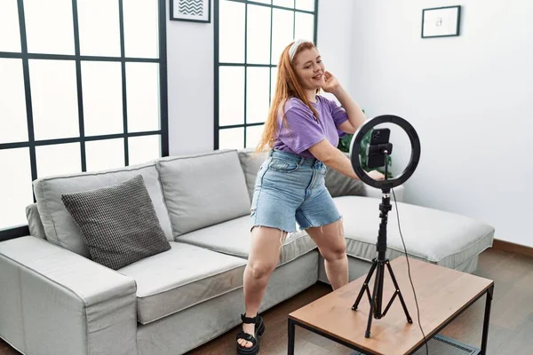 stock image Young redhead woman having video call dancing at home