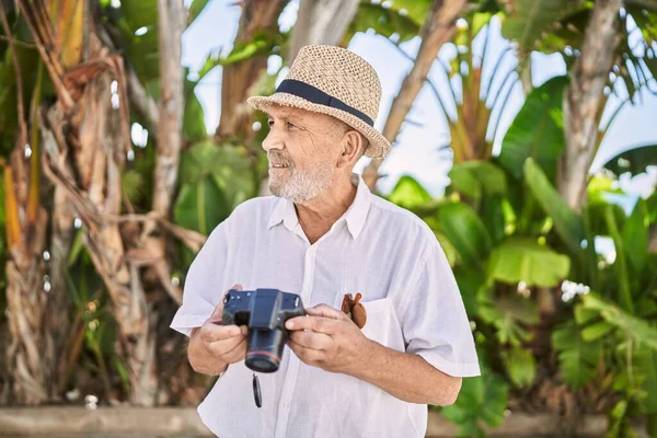 Homem Sênior Sorrindo Confiante Usando Chapéu Verão Usando Câmera Parque — Fotografia de Stock