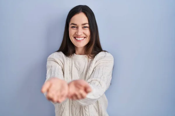 Jonge Brunette Vrouw Staat Blauwe Achtergrond Glimlachend Met Handen Palmen — Stockfoto