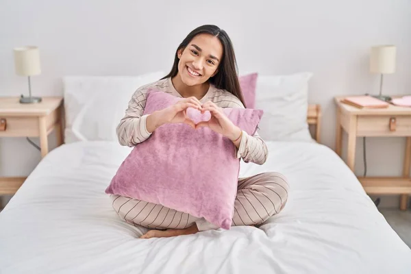 Young Hispanic Woman Doing Heart Gesture Sitting Bed Bedroom — Stockfoto