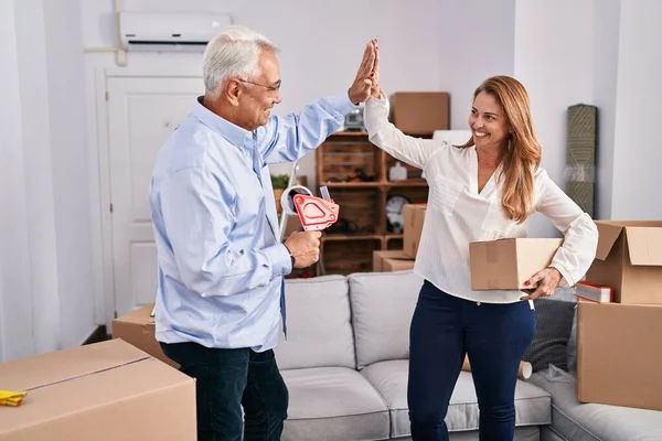 Middle age man and woman couple high five with hands raised up at new home