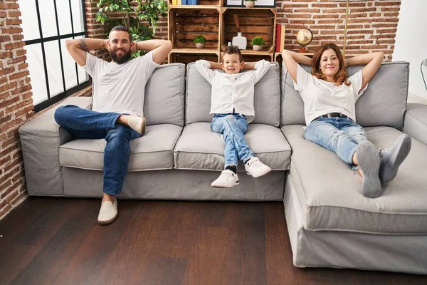 Family relaxed with hands on head sitting on sofa at home
