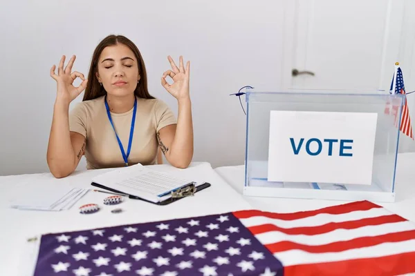 Young brunette woman at political election sitting by ballot relax and smiling with eyes closed doing meditation gesture with fingers. yoga concept.