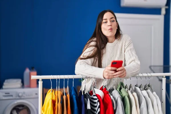Mujer Morena Joven Esperando Lavandería Con Smartphone Haciendo Cara Pez — Foto de Stock