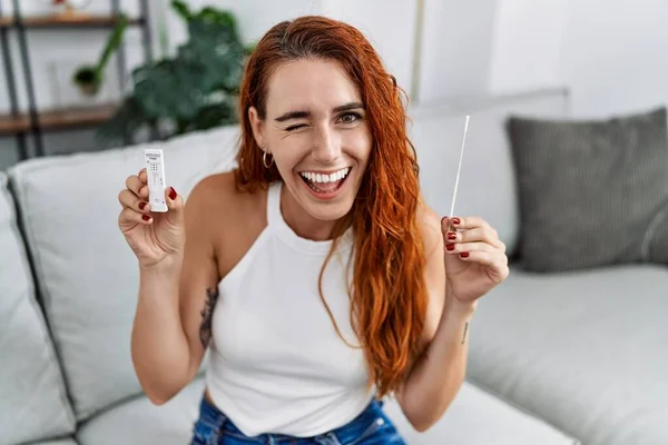 Young Redhead Woman Doing Coronavirus Infection Nasal Test Winking Looking — Stock Photo, Image