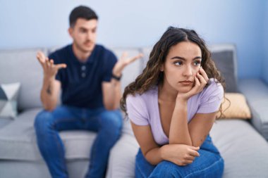Young hispanic couple arguing sitting on sofa at home