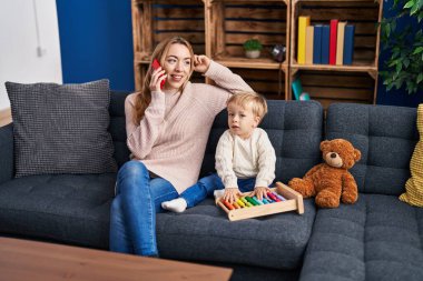 Mother and son talking on the smartphone and playing with abacus at home