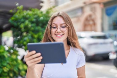 Genç sarışın kadın gülümsüyor. Caddedeki dokunmatik evde video izlerken kendinden emin.