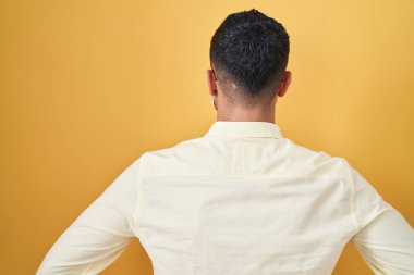 İş kıyafetleri ve gözlük takmış İspanyol genç adam kolları vücudunda geriye doğru bakıyor. 