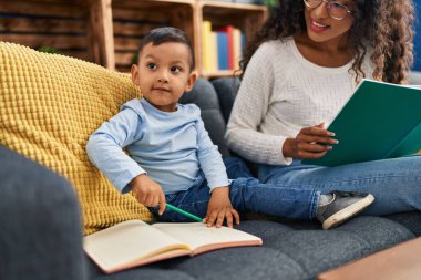 Mother and son sitting on sofa drawing at home